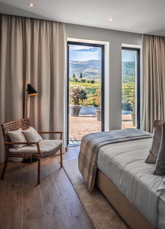 um quarto com uma cama, uma cadeira e uma janela em Quinta da Salada - Turismo Rural em Lamego