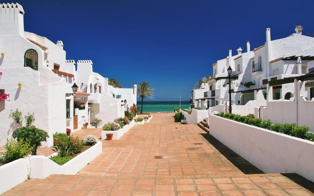 una pasarela entre edificios blancos con el océano en el fondo en Costa del Sol, Puerto de la Duquesa, en Castillo de Sabinillas