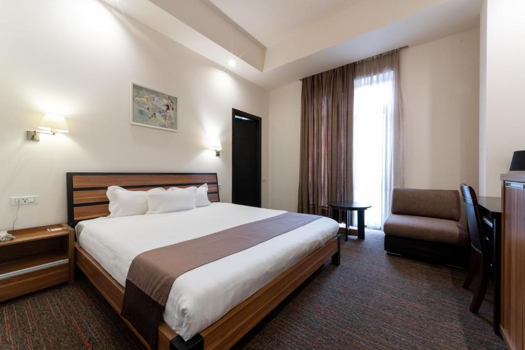 Habitación de hotel con cama y silla en Bass Boutique Hotel, en Ereván