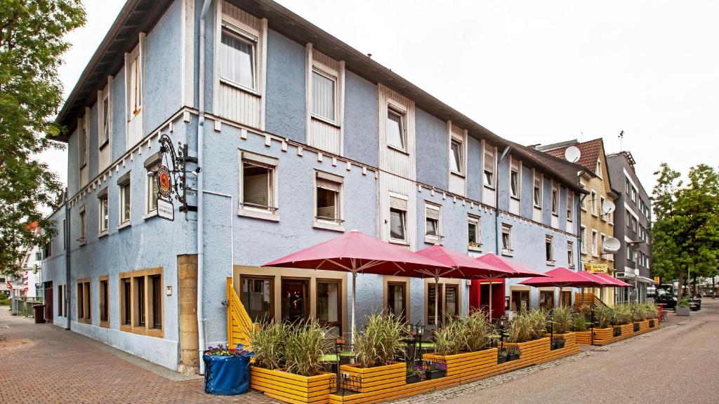 a large building with red umbrellas on a street at Hotel Scharfes Eck in Mühlacker