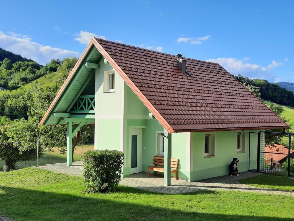 uma pequena casa verde e branca com um cão em Holiday Home Neokrnjena Narava em Sevnica