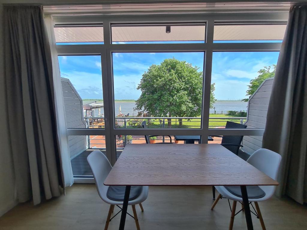 a table and chairs in front of a large window at Apartments Gezeitenfluss in Tönning