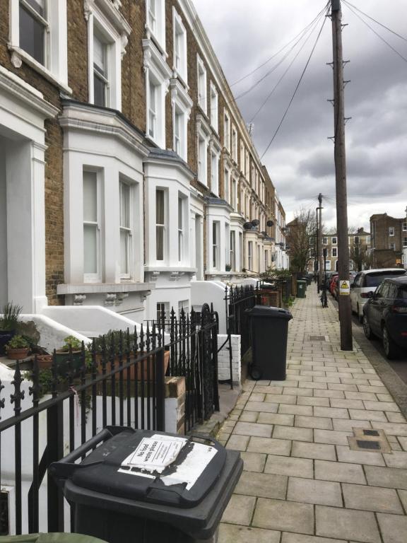a street with buildings and a bench on a sidewalk at CLASSIC BRIXTON CITY APARTMENT in London