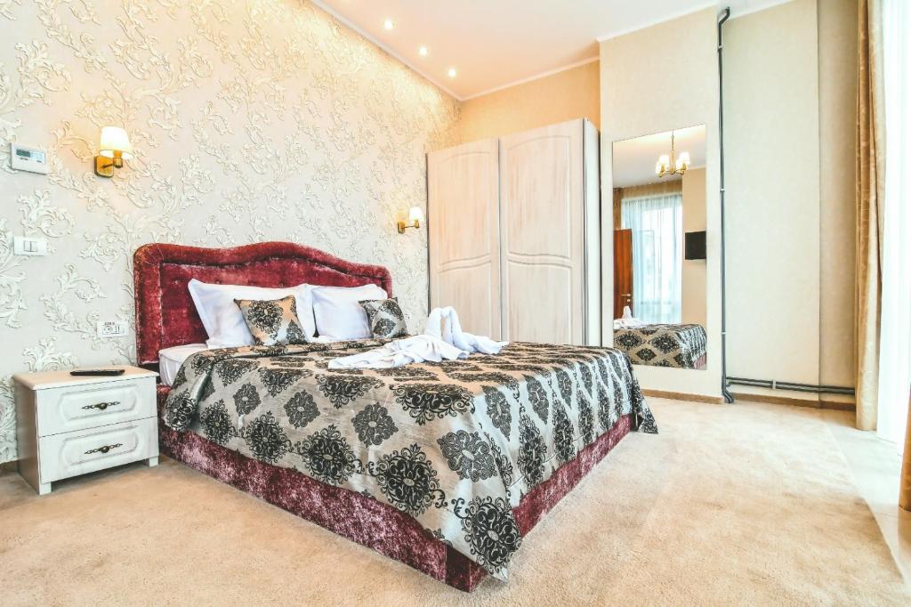 a bedroom with a large bed and a mirror at IMPERA Boutique Apartments in Constanţa