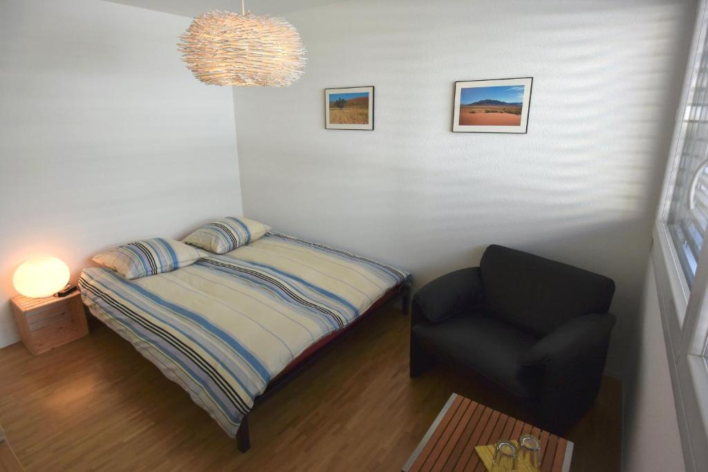 um pequeno quarto com uma cama e uma cadeira em BnB 5430 em Wettingen