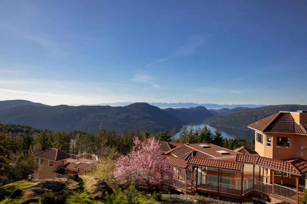 a house on a hill with mountains in the background at Villa Eyrie Resort in Malahat