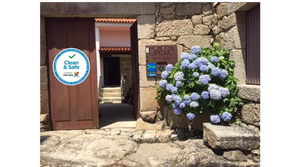 un cartello davanti a una porta con un cespuglio di fiori viola di Casa Da Trigueira a Santa Eugénia