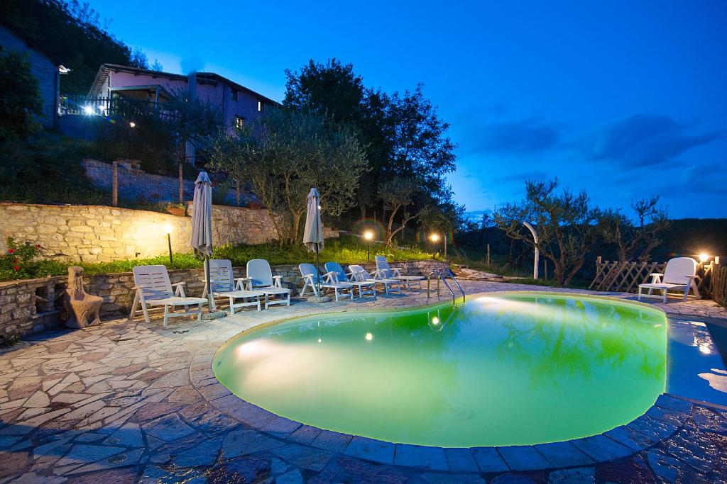 a swimming pool at night with chairs and umbrellas at Coldipietra in Cessapalombo