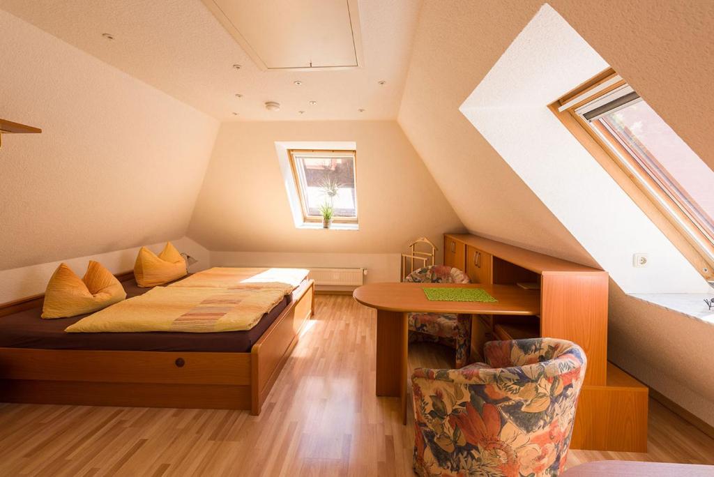 um quarto no sótão com uma cama e uma mesa em Numero1-Pension und Cafe em Rübeland