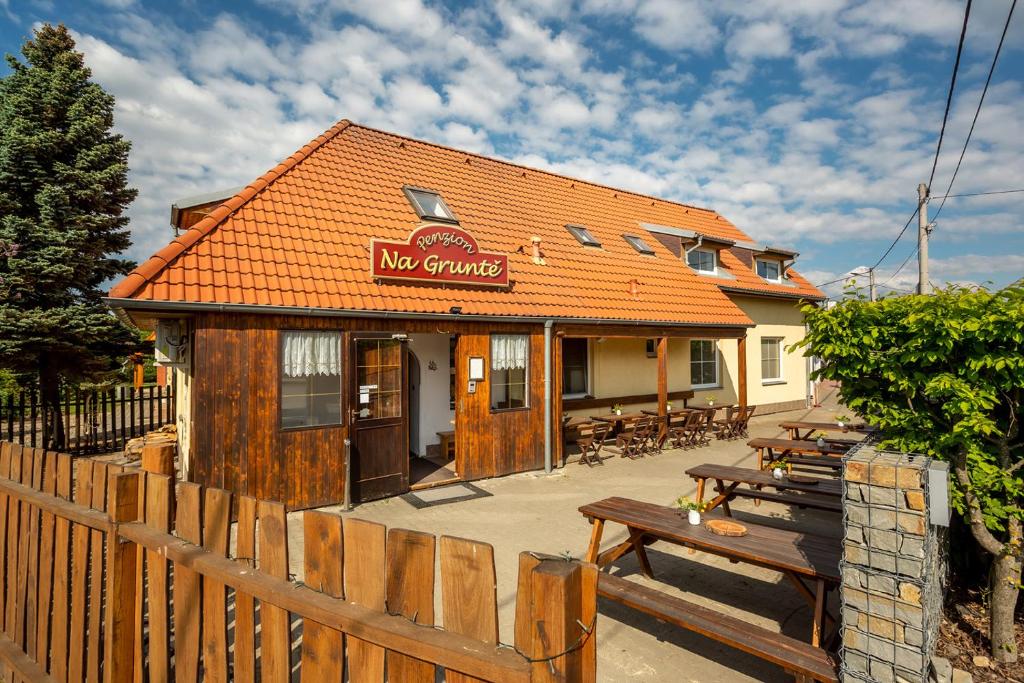 un restaurant avec un toit orange et une clôture en bois dans l'établissement Penzion Na Gruntě, à Vranov nad Dyjí