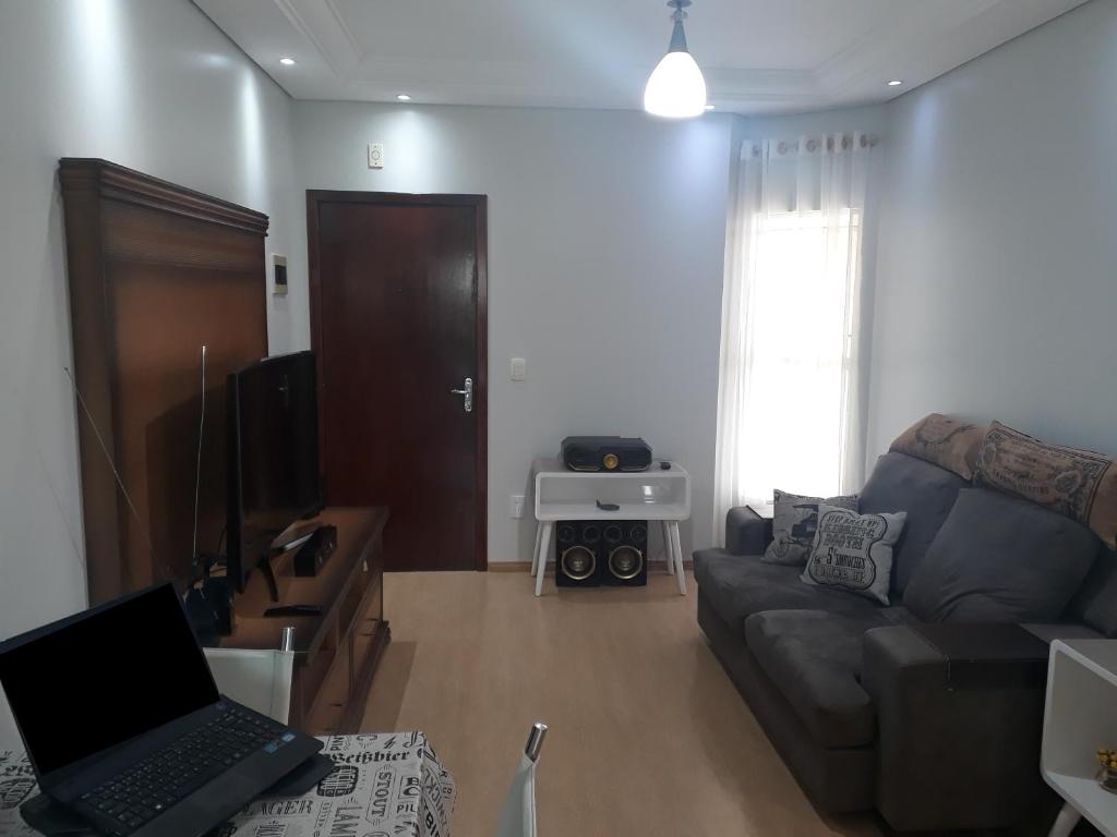 a living room with a couch and a laptop at Apto Residencial Saguaçu in Joinville