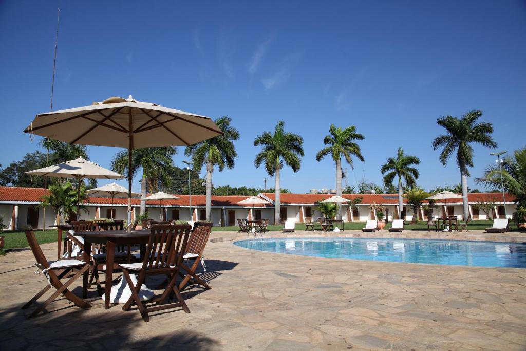 a table and chairs with an umbrella next to a pool at IPÊ PARK Convention Hotel in Sao Jose do Rio Preto