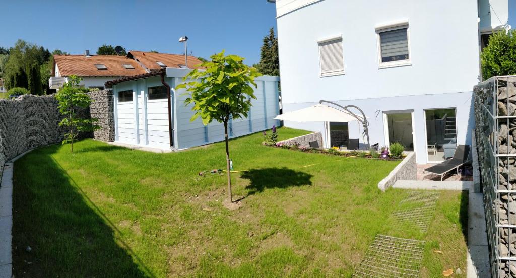 ein kleiner Baum in einem Hof neben einem weißen Haus in der Unterkunft Casa Elea, die Ferienwohnung mit Terrasse und Garten am Tor zum Bodensee in Stockach