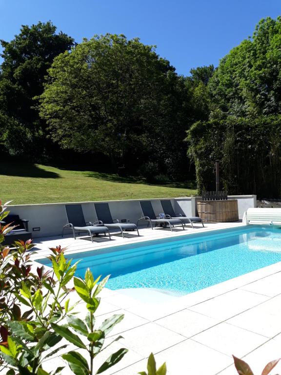 a swimming pool with lounge chairs next to at B&B "Le Parc des 4 Saisons" in Corrèze