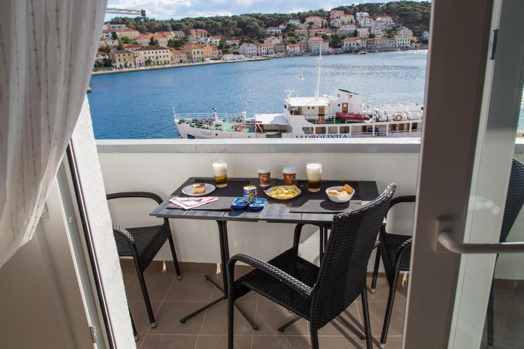 a table on a balcony with a view of a boat at Apartment Gordon in Mali Lošinj
