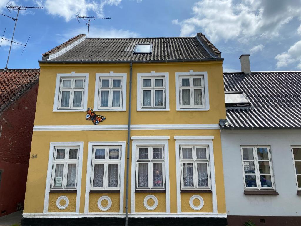 Casa blanca y amarilla con ventanas blancas en Holiday rooms Rudkøbing, en Rudkøbing