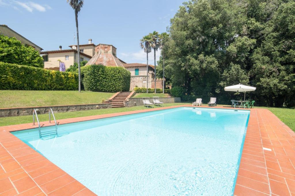 een groot zwembad met stoelen en een parasol bij Villa Ott in Crespina