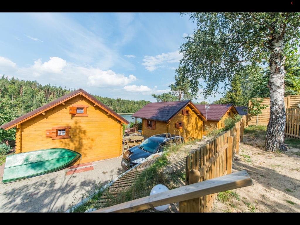 a house with a surfboard and a car parked in front of it at Domki letnisowe w sercu Kaszub Dziemiany in Dziemiany