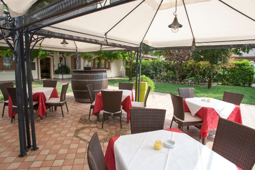 un patio con mesas y sillas bajo una sombrilla en Hotel Ristorante Alla Botte, en Portogruaro