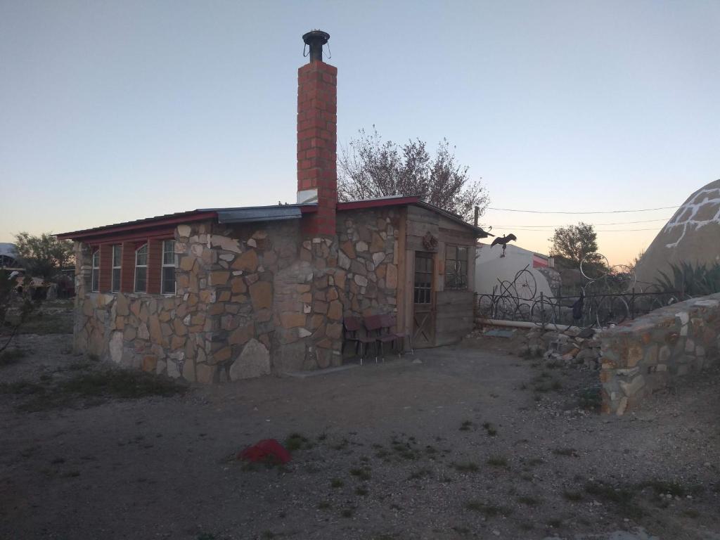 a stone house with a brick chimney and a fence at La loma del chivo Llc Stone Cottage alternative building in Marathon