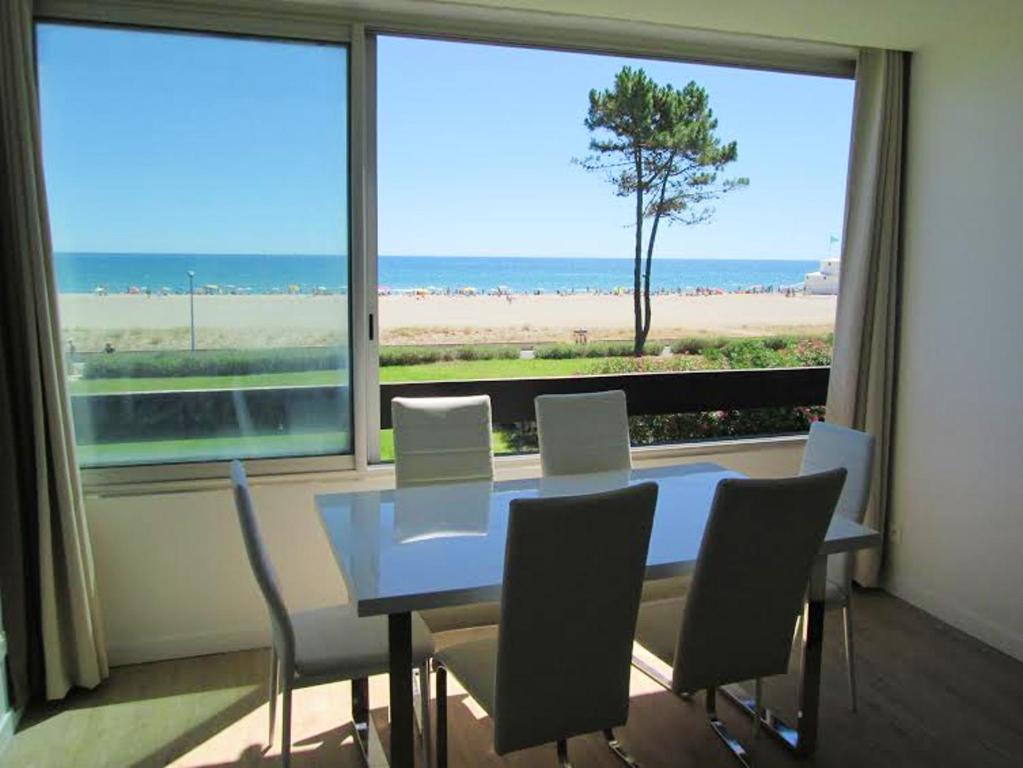 a dining room table with chairs and a view of the beach at Appartement lumineux à Saint-Cyprien 45 m² vue mer in Saint-Cyprien