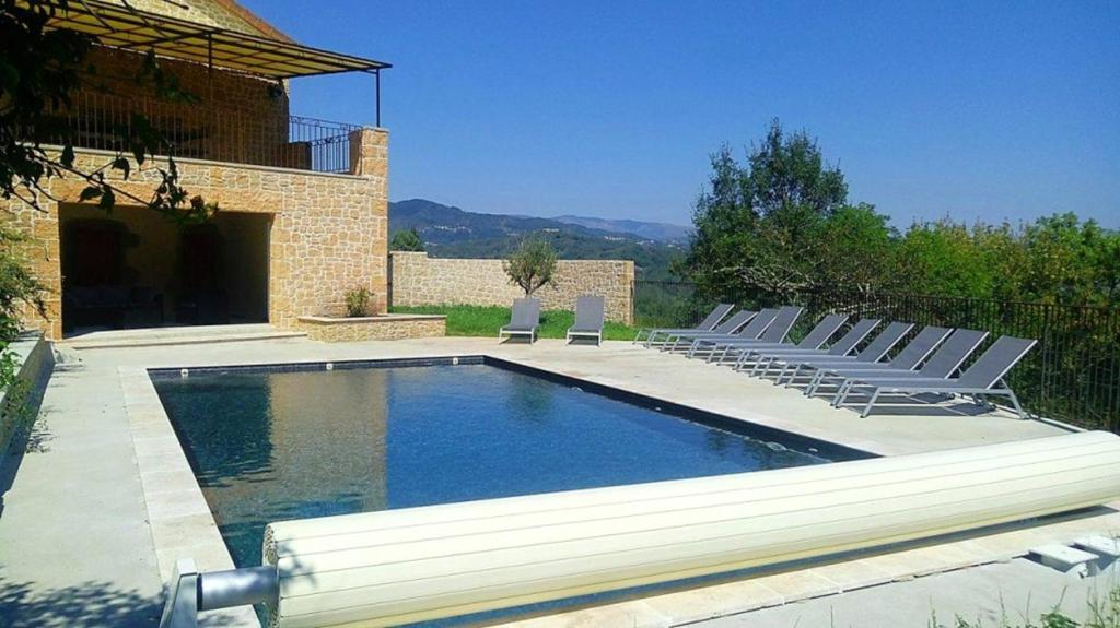 a swimming pool with lounge chairs next to a house at Villa de 4 chambres avec piscine privee jacuzzi et jardin clos a Prades in Prades
