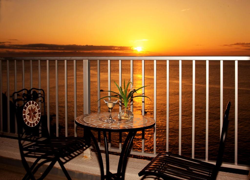 een tafel met wijnglazen op een balkon met een zonsondergang bij Shirahama Beach 312 in Shirahama