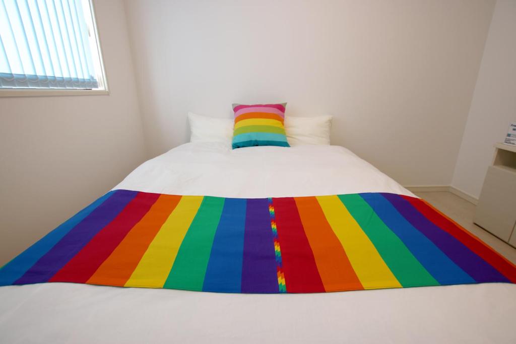 a rainbow blanket on top of a bed at KOEI FARM LODGE -SEVEN Hotels and Resorts- in Kin