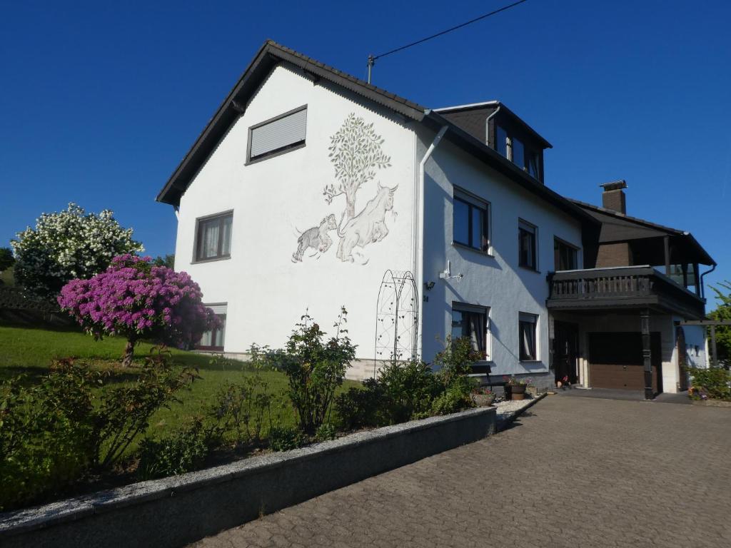 ein weißes Haus mit einem Wandbild an der Seite in der Unterkunft Ferienwohnung Fülbier in Oberzissen