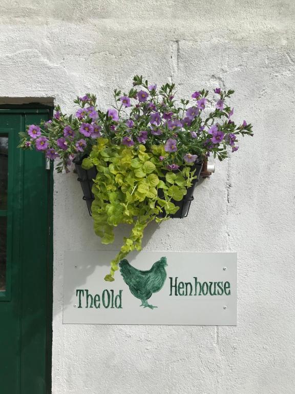een bord voor het oude kippenhok met bloemen en een kip bij The Old Henhouse in Tollarp