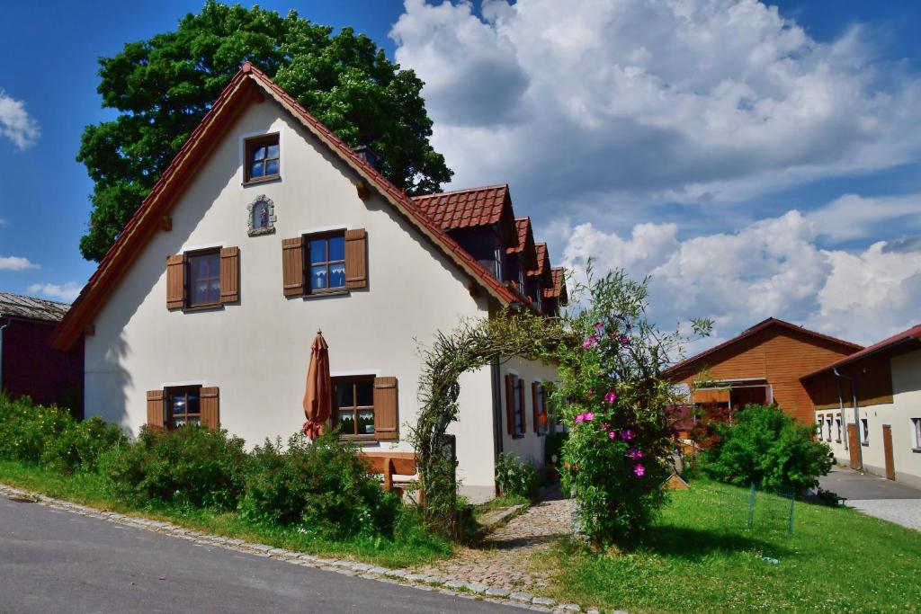 een wit huis met bruine ramen en een tuin bij Ferienwohnung Burgerhof in Pullenreuth