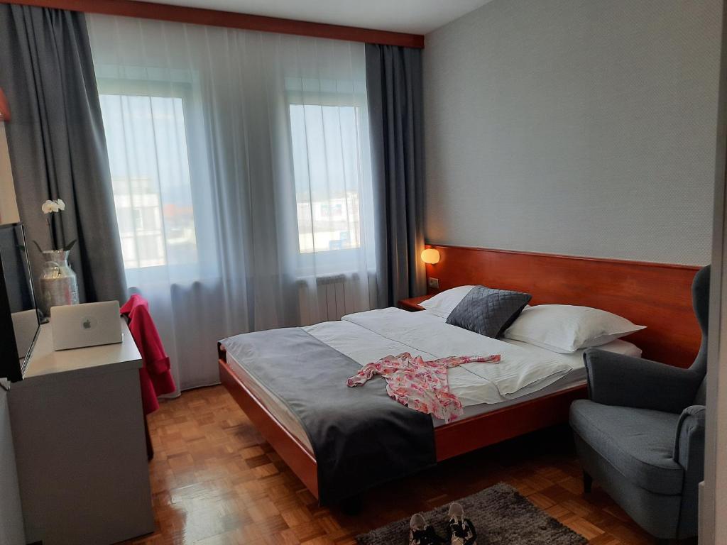 a bedroom with a bed and a chair and windows at Hotel Vodisek in Koper