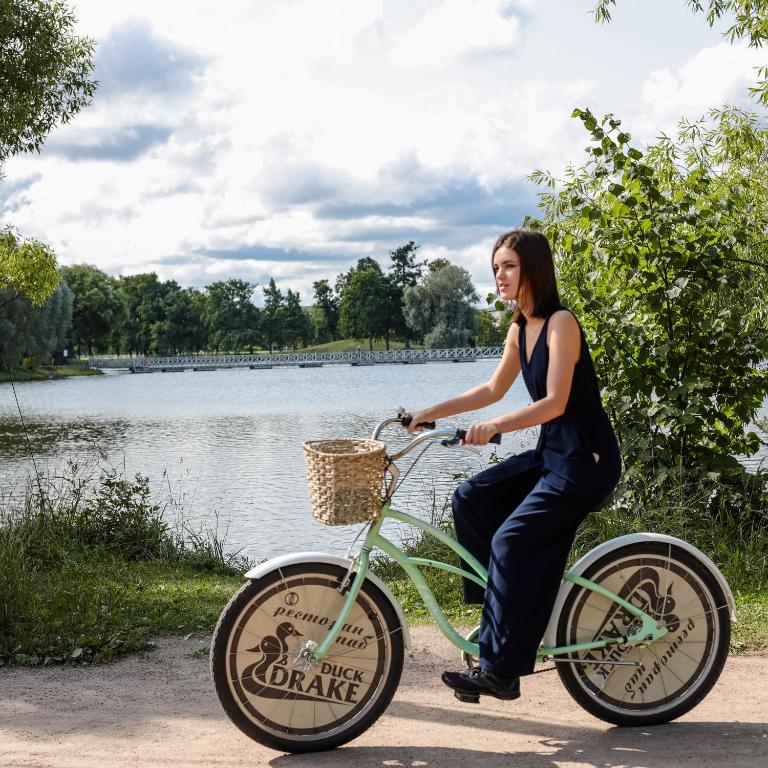 a woman riding a bike next to a lake at New Peterhof Hotel in Petergof
