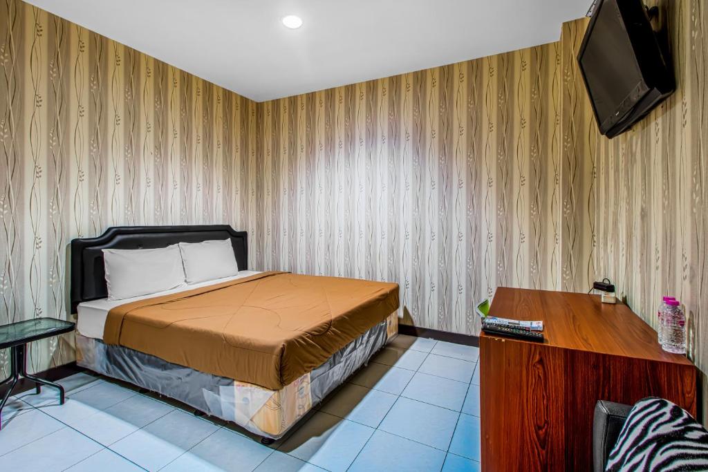 1 dormitorio con 1 cama y TV en la pared en Griya Stadion en Semarang