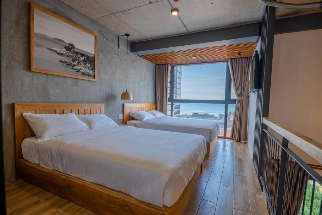 a hotel room with two beds and a large window at Coast House Boutique Hotel in Nha Trang