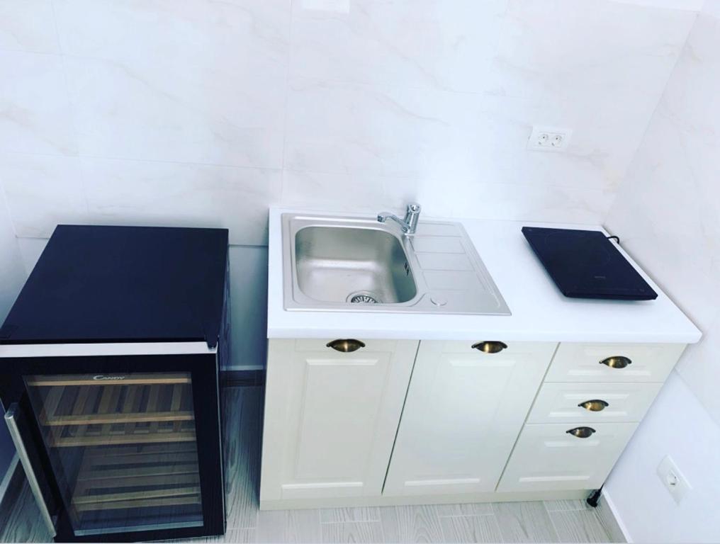 a white kitchen with a sink and a shelf at Studio Katerina in Mamaia