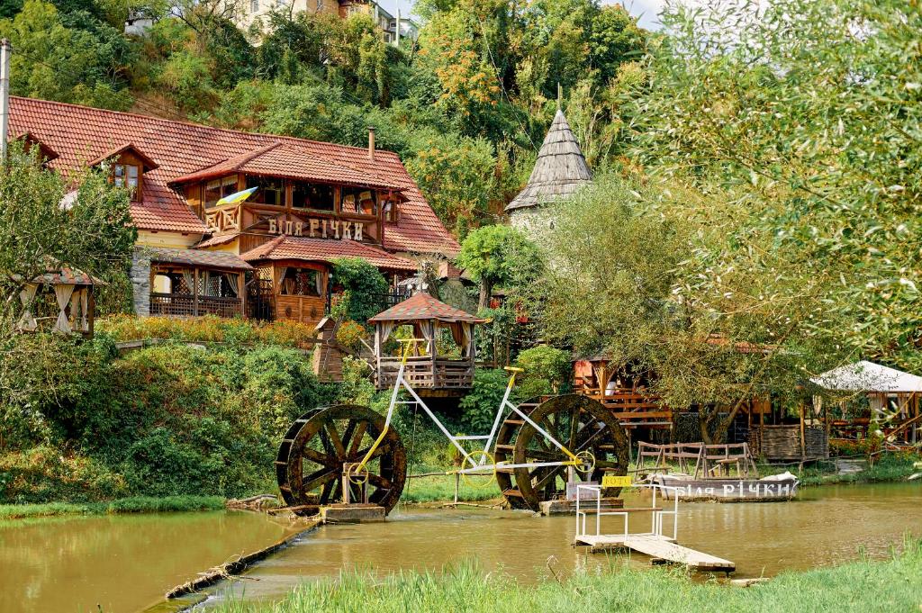 ein Holzhaus mit einem Traktor im Wasser in der Unterkunft Bilya Richky Hotel in Kamjanez-Podilskyj