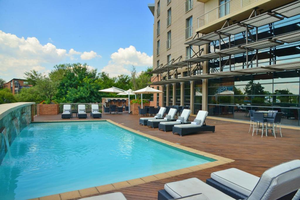 a swimming pool with lounge chairs next to a building at City Lodge Hotel Fourways in Johannesburg