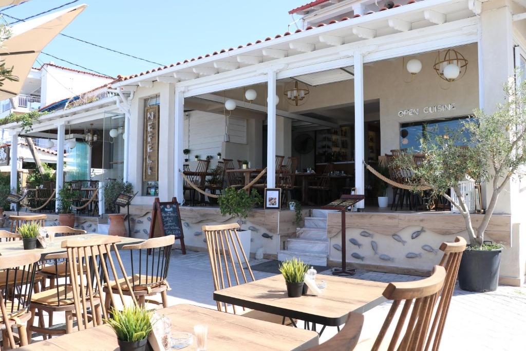 un restaurante con mesas de madera y sillas frente a él en Nefeli Seaside Apartments, en Polychrono