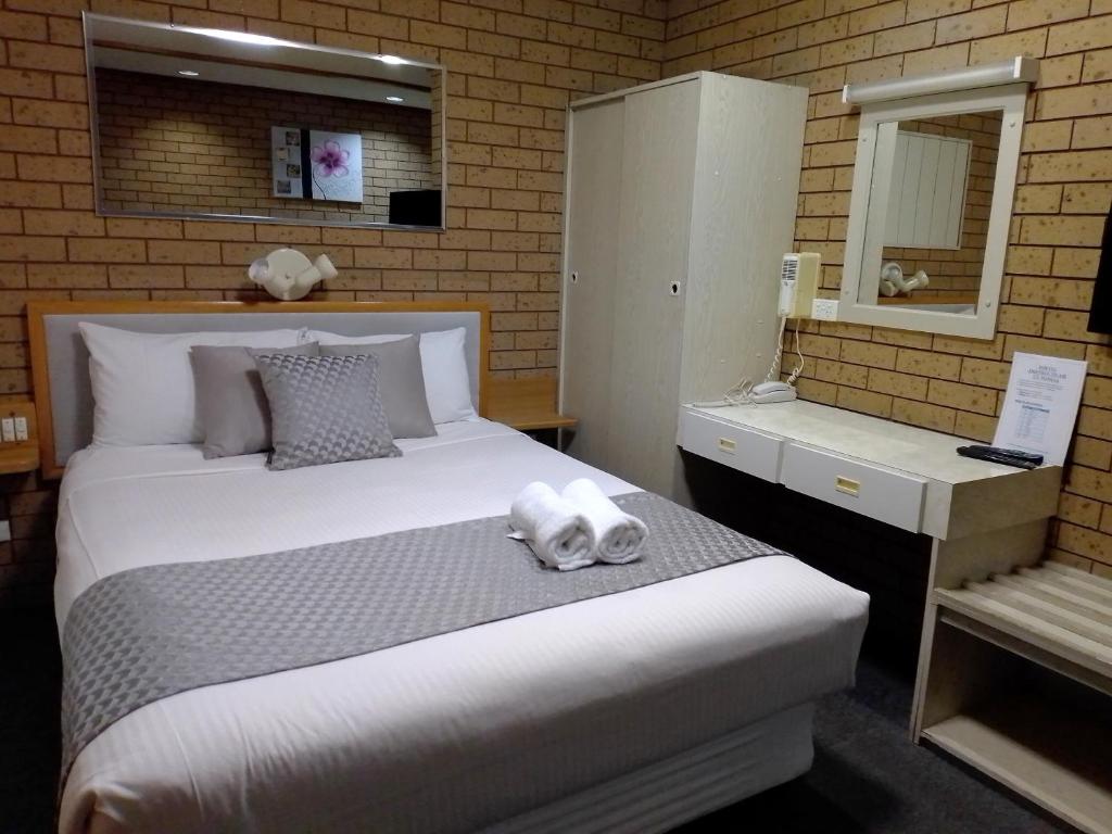 a bedroom with a large white bed and a mirror at Country Home Motor Inn in Shepparton