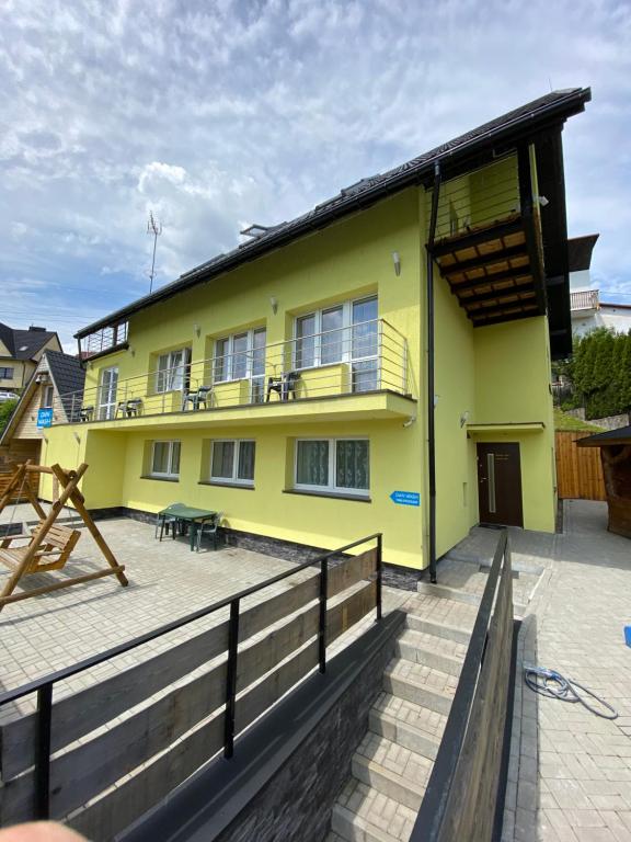 a yellow house with a balcony and a patio at Pokoje i apartamenty Aga Centrum in Wisła