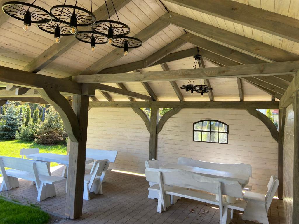 Drewniana pergola z białymi krzesłami i stołami w obiekcie D.W Nawigator w Ostrowie