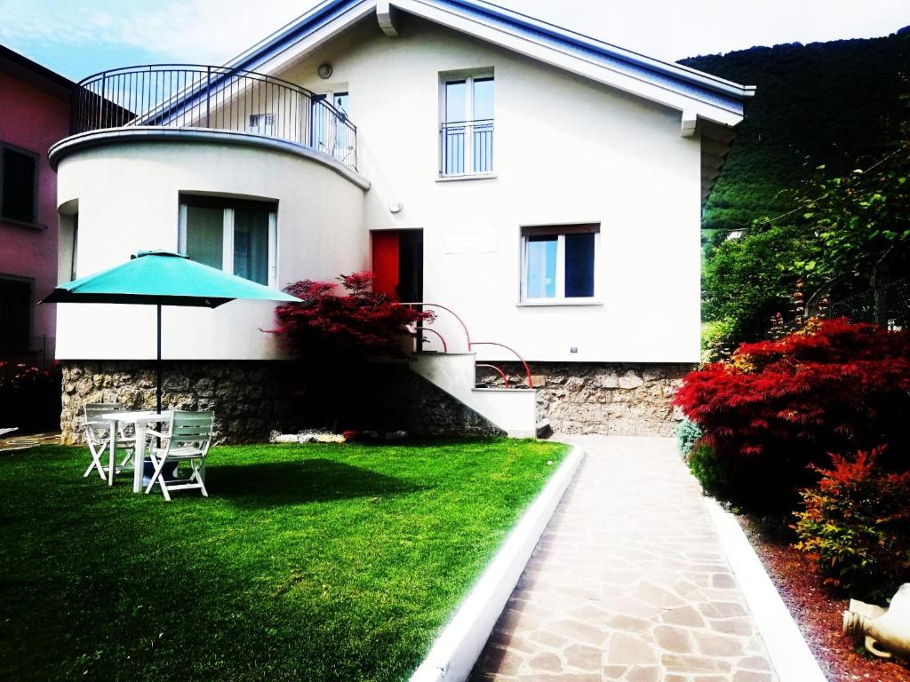 een wit huis met een tafel en een paraplu bij Villa Harriet in Sovere