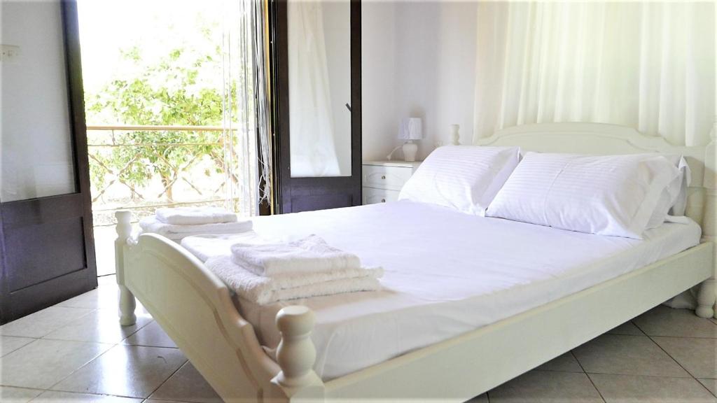 a bedroom with a white bed with towels on it at Amarynthos Beachfront Vacation House with garden in Áno Váthia