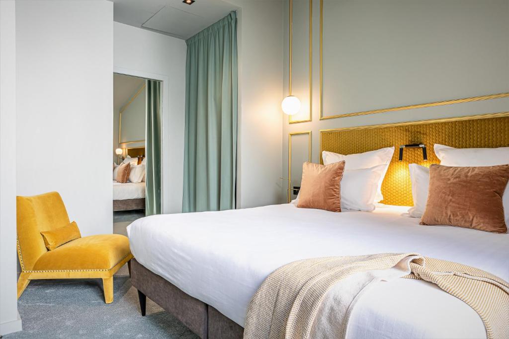 パリにあるHôtel Veryste & Spa Parisの大きなベッドと椅子が備わるホテルルームです。