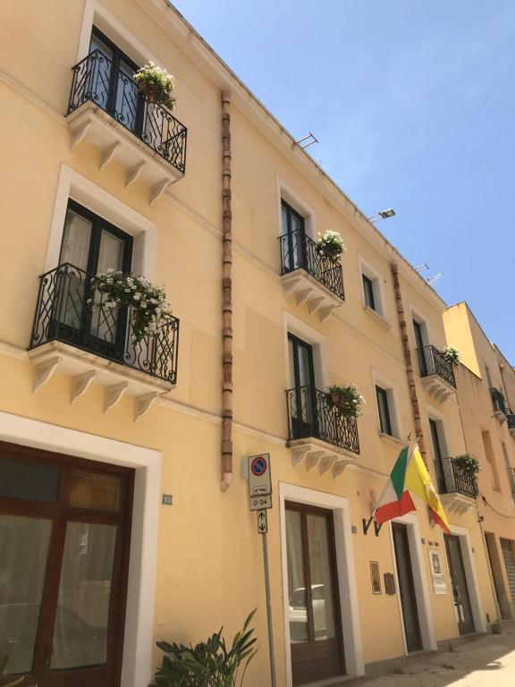 a building with balconies and a flag on a street at San Domenico Residence by BADIA NUOVA in Trapani