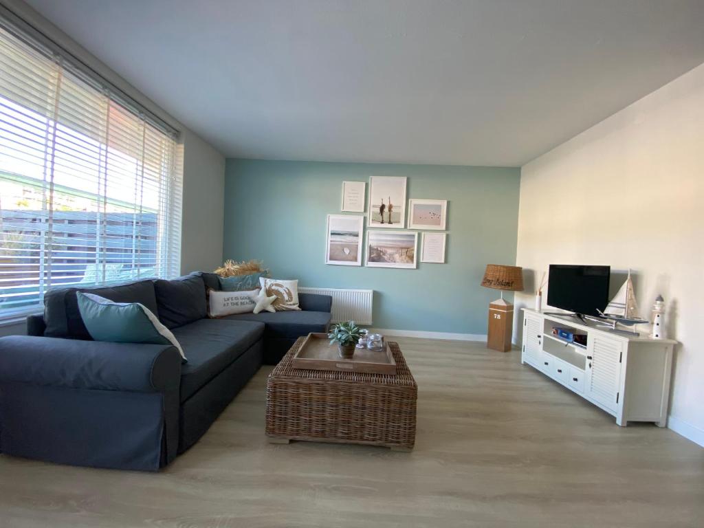 sala de estar con sofá azul y TV en Casa del Mar Zandvoort, en Zandvoort
