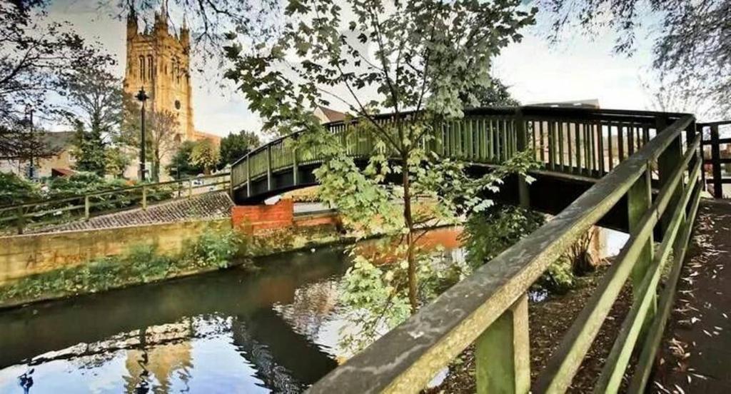 un puente sobre un río con una torre de reloj en River View House St Neots - Navigation Wharf, en Saint Neots