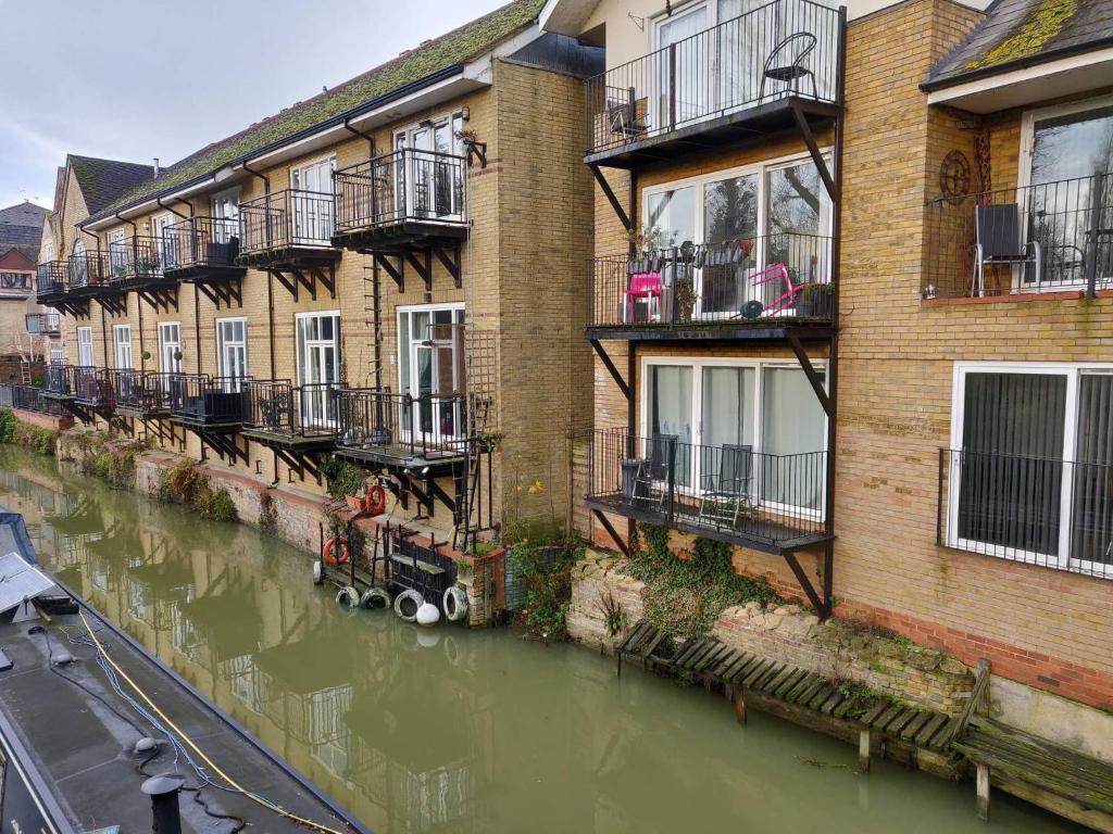a row of apartment buildings next to a river at Waterfront Apartment In The Heart Of St Neots in Saint Neots