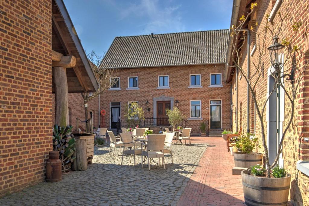 un patio con sillas, mesas y edificios de ladrillo en Auberge de Smockelaer, en Heijenrath